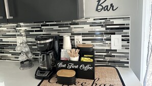 Eine Küche mit einer Kaffeebar-Beschilderung, einer Kaffeemaschine, Tassen und einer Packung Swiss Miss Kaffee.