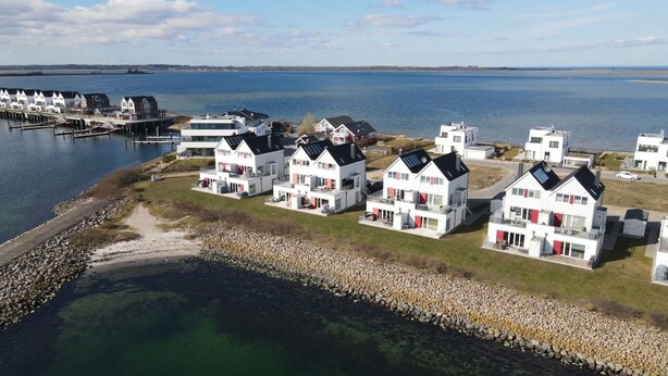 A coastal residential area with modern white houses, a marina, and a clear view of the sea. - Maisonette Fewo Ostseeflair Erste Wasserreihe, Panoramablick, by Seeblick Ferien (Kappeln)