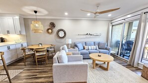 A modern living room with a sofa, armchairs, a coffee table, and a dining area with a table and chairs. - BEACHFRONT Townhome - New Kitchen and Bath - 2 BR 2.5 Bath   (Gulf Shores)