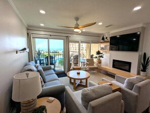 A modern living room with a sofa, armchairs, a coffee table, a TV, and a fireplace.