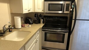 A kitchen with a sink, two ovens, a microwave, and a refrigerator. - Villa-style condo with pool and beach access - Condo 8 (Holmes Beach)