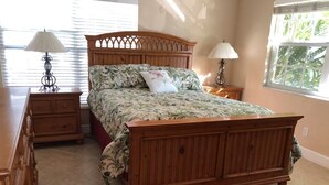 A bedroom with a wooden bed, two bedside tables with lamps, a dresser, and a window with blinds. - Villa-style condo with pool and beach access - Condo 8 (Holmes Beach)
