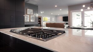 A modern kitchen with a central island, dark cabinetry, and recessed lighting. - DisneyFun _Pool _Hot Tub _5 bedroom _EV Charger (Anaheim)