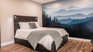 A bedroom with a bed, a headboard, a wall mural of a forest and mountains, and wooden flooring. - DisneyFun _Pool _Hot Tub _5 bedroom _EV Charger (Anaheim)