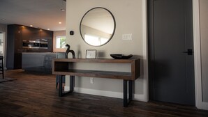 A modern kitchen with a wooden bench, a round mirror, and a dark door. - DisneyFun _Pool _Hot Tub _5 bedroom _EV Charger (Anaheim)