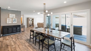 A spacious dining area with a long wooden table, multiple chairs, and a modern chandelier. - DisneyFun _Pool _Hot Tub _5 bedroom _EV Charger (Anaheim)