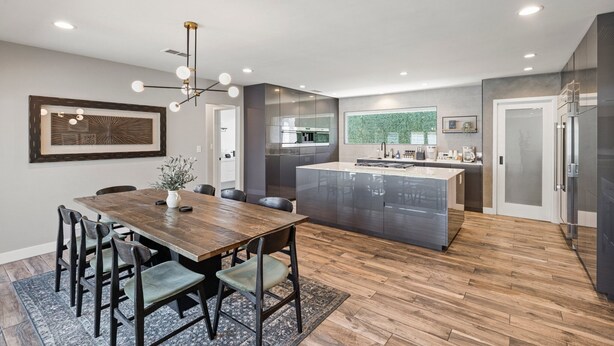 A modern kitchen with a central island, built-in appliances, and a dining area with a wooden table and chairs. - DisneyFun _Pool _Hot Tub _5 bedroom _EV Charger (Anaheim)