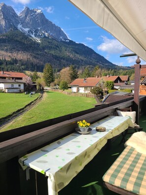 Una terraza con mesa lista para comer, con vistas a un pueblo y montañas.