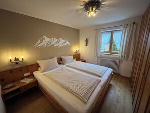 A double bed with checkered bedding, a wall-mounted light, and a mountain mural.