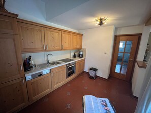 A kitchen with wooden cabinets, a stainless steel sink, a coffee maker, and a trash bin. - Frühholz—The Vacation Home, 5-Star "Wank" Apartment in Grainau & Shared Garden (Grainau)