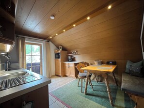 A cozy kitchen with wooden cabinets, a dining table, and a window with curtains.