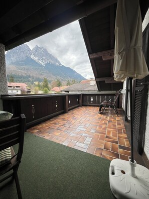 A balcony with a tiled floor, a chair, and an umbrella.
