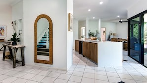 A modern kitchen with a central island, a large mirror, and a staircase leading to another level. - The Palms - Hamilton Island (Hamilton Island)