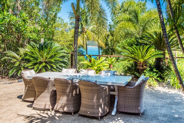 An outdoor dining area with wicker furniture and a view of the ocean.