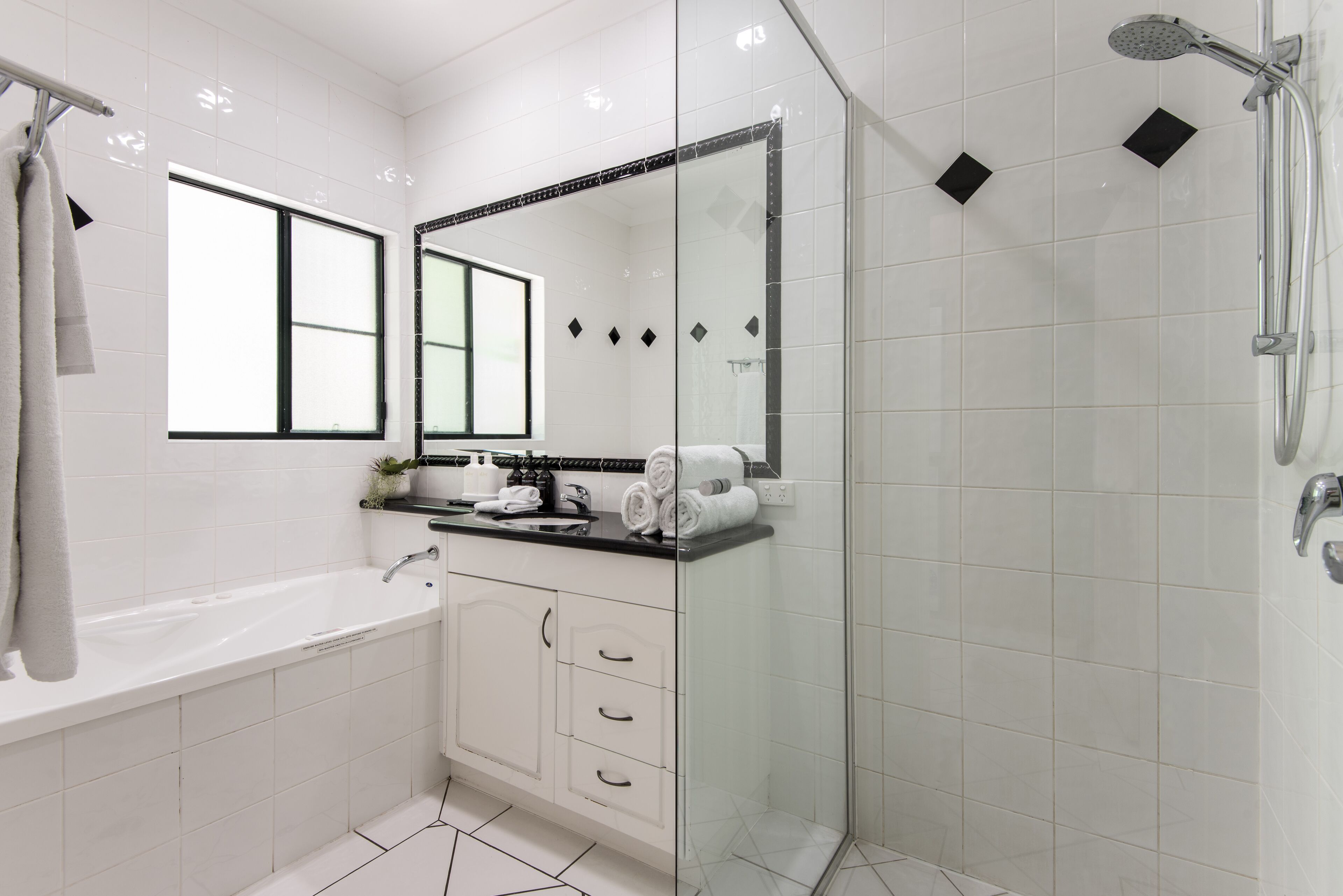 A modern bathroom with a glass-enclosed shower, a large mirror, and a white sink with a countertop.