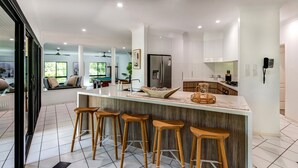 A modern kitchen with a central island, bar stools, and a refrigerator. - The Palms - Hamilton Island (Hamilton Island)