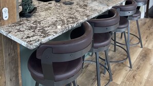 Une cuisine dotée d’un comptoir en granit, de tabourets de bar, d’un éclairage suspendu et offrant une vue sur l’espace repas.