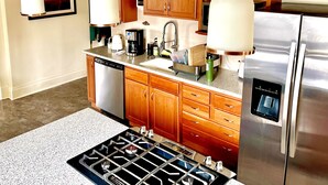 A modern kitchen with wooden cabinets, stainless steel appliances, and pendant lighting. - Classic uptown mansion (Butte)