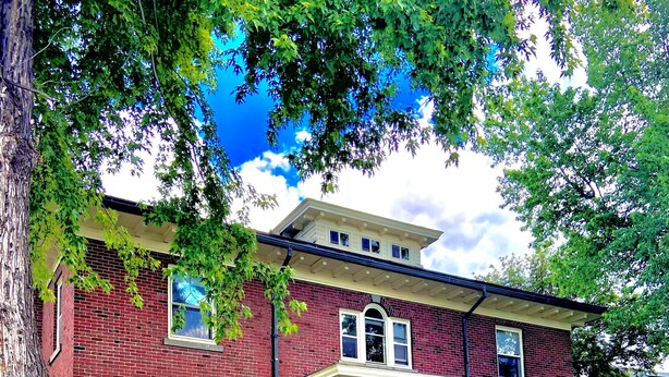 A two-story brick house with a front porch, a small upper level, and a visible front door. - Classic uptown mansion (Butte)
