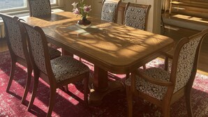 A dining room with a wooden table, patterned chairs, a chandelier, and a view through a window. - Classic uptown mansion (Butte)