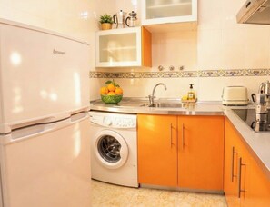 Eine kompakte Küche mit Waschmaschine, Spüle und einem Benarent-Kühlschrank.