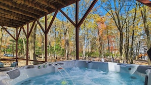 A hot tub area with a wooden pergola overhead, surrounded by trees with autumn foliage. - Peaceful fully renovated chalet in Lake Harmony, dog friendly! (Lake Harmony)