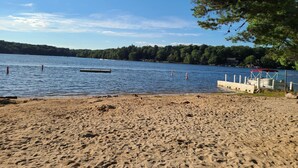 A sandy beach with a dock and a boat. - Peaceful fully renovated chalet in Lake Harmony, dog friendly! (Lake Harmony)