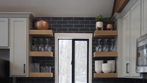 A modern kitchen with white cabinets, a black backsplash, and a window above the sink. - Peaceful fully renovated chalet in Lake Harmony, dog friendly! (Lake Harmony)