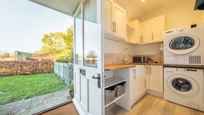 Una cucina moderna con mobili bianchi, lavatrice integrata e vista sul giardino.