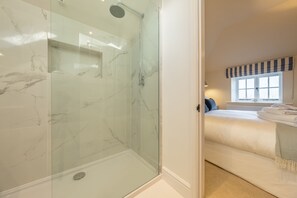 A modern bathroom with a glass-enclosed shower and a separate bedroom with a bed and a window. - The Coach House (R), Ringstead, Norfolk (Ringstead)