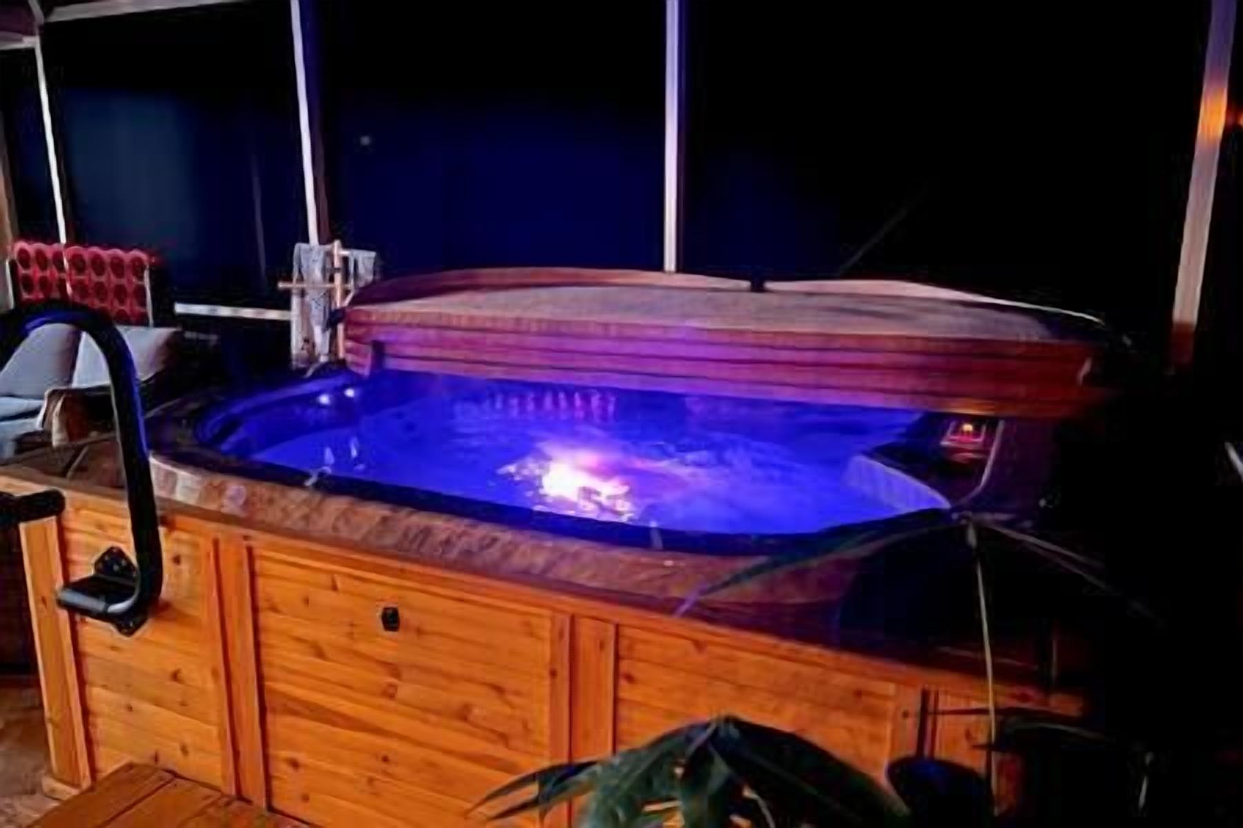 Ein Whirlpool mit Holzverkleidung und Glasabdeckung, umgeben von einem dunklen Raum.