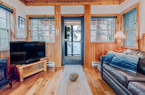 A cozy living room with a wooden floor, a leather sofa, a television, and a stone centerpiece.