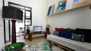 Un saló amb un sofà, una televisió, una planta i obres d'art a la paret.
