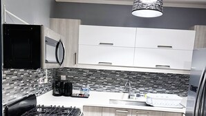 Una cocina moderna con estufa a gas, electrodomésticos de acero inoxidable y salpicadero de azulejos blanco y negro.