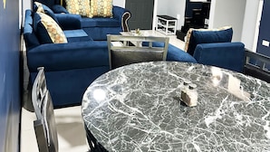 Una sala de estar moderna con un sofá azul, una mesa de centro de mármol y una puerta gris.