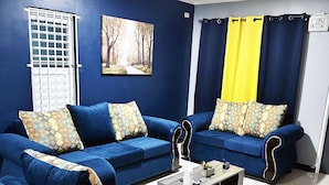Una sala de estar con dos sofás azules, una mesita de centro y un cuadro en la pared.
