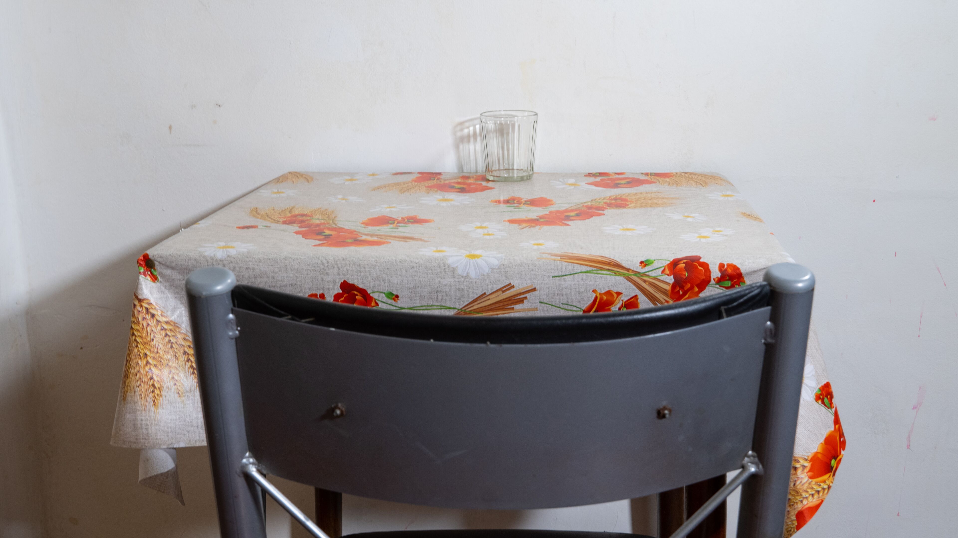 A small table with a floral tablecloth and a clear glass.