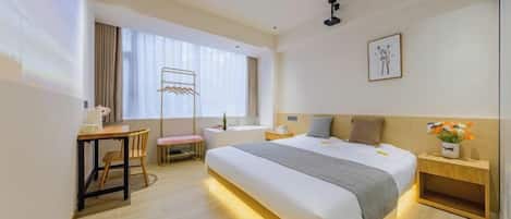 Habitación de hotel con una cama grande, un escritorio, una silla y un ventanal con cortinas.