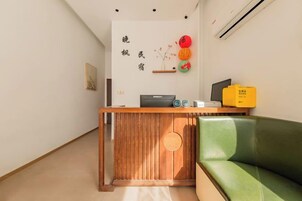 Una recepción con encimera de madera, un sofá verde y una pared con detalles decorativos.