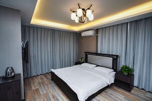 Un dormitorio moderno con una cama grande, mesitas de noche, una lámpara de techo y un aire acondicionado instalado en la pared.
