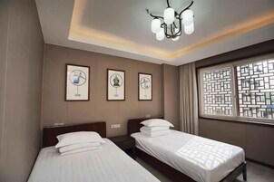 Habitación de hotel con dos camas, una araña y obras de arte en la pared.