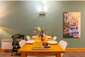 Una mesa de comedor preparada con platos, una botella y una fuente de queso.