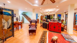 A spacious living room with a high ceiling fan, a staircase, and a red cabinet. - Pool Villa with maid service- walk to white sand beach! (Paknampran)