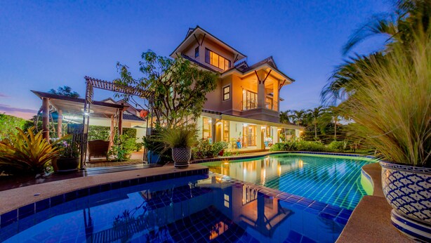 A large house with a swimming pool, surrounded by tropical plants and a pergola. - Pool Villa with maid service- walk to white sand beach! (Paknampran)
