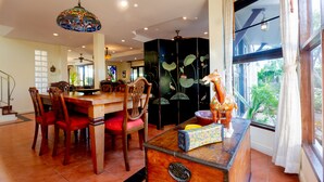 A dining area with a wooden table, chairs, and a decorative cabinet. - Pool Villa with maid service- walk to white sand beach! (Paknampran)
