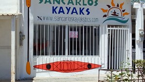 Um edifício com uma placa indicando 'SANCARLOS KAYAKS' e um endereço de site.