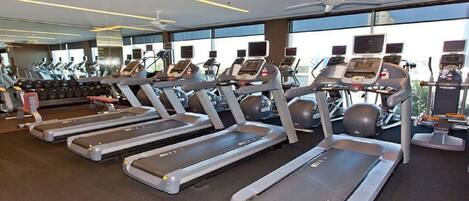 A gym with treadmills, exercise bikes, and a large mirror.