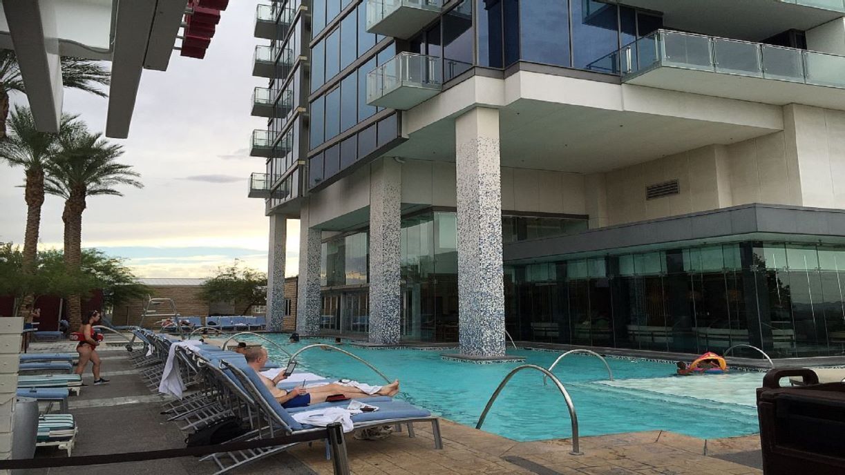 Un hôtel moderne doté d’un espace piscine, comprenant des chaises longues et offrant une vue dégagée sur la piscine.