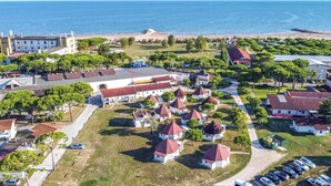 An aerial view of a coastal town with a beach, a large white building, and several red-roofed structures. - Nice home in Cavallino-Treporti (Cavallino-Treporti)