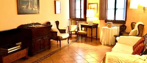 A cozy hotel room with a dining area, a painting on the wall, and a tiled floor.